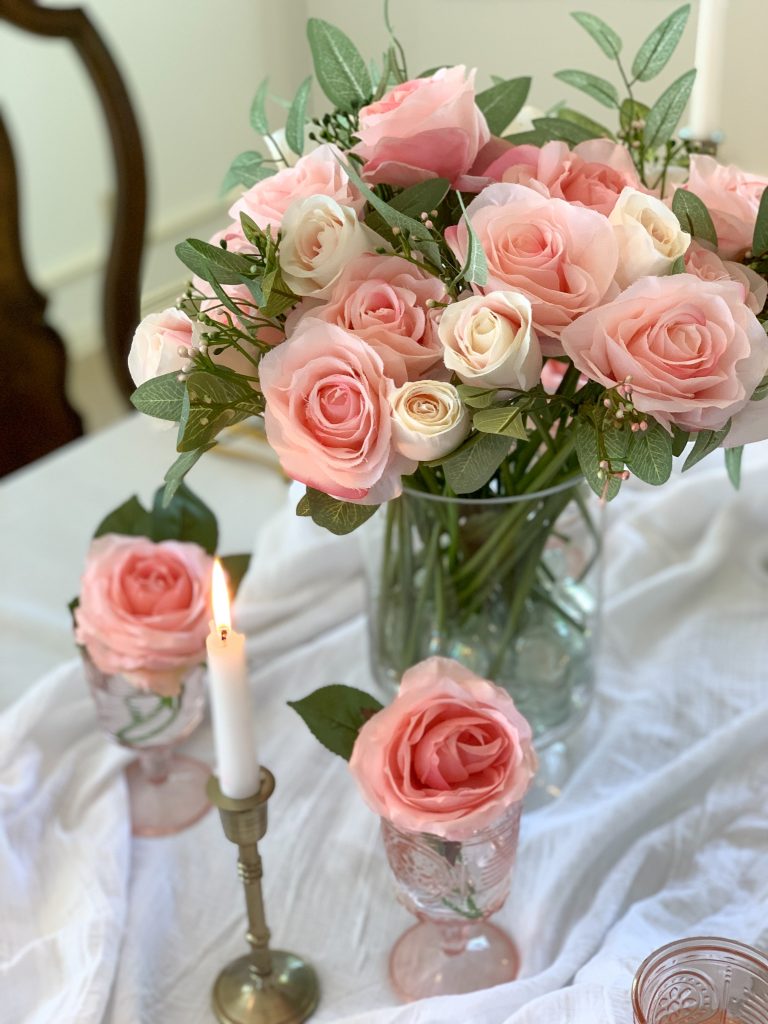 A faux rose centerpiece on a beautiful pink table setting.