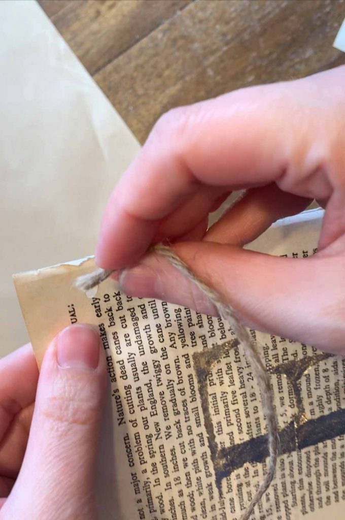 A piece of twine is being put through a hole of a vintage book page.