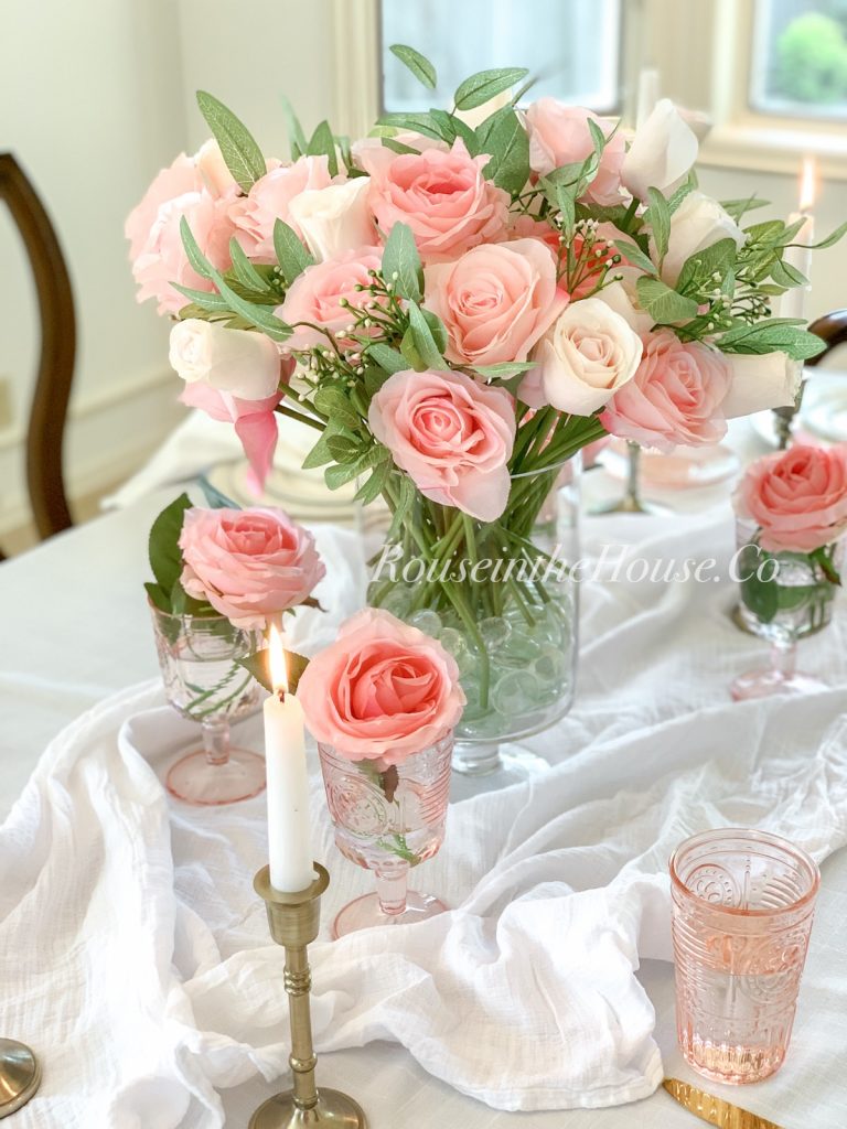 A Peachy Pink Rose arrangement on a tabletop with pink depression glass