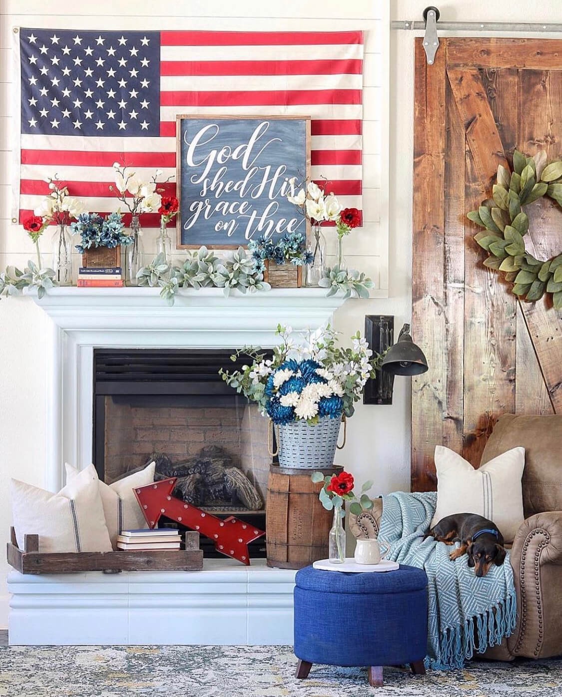 A mantel has a US flag, a God Shed his Grace on thee signs, and patriotic decor.