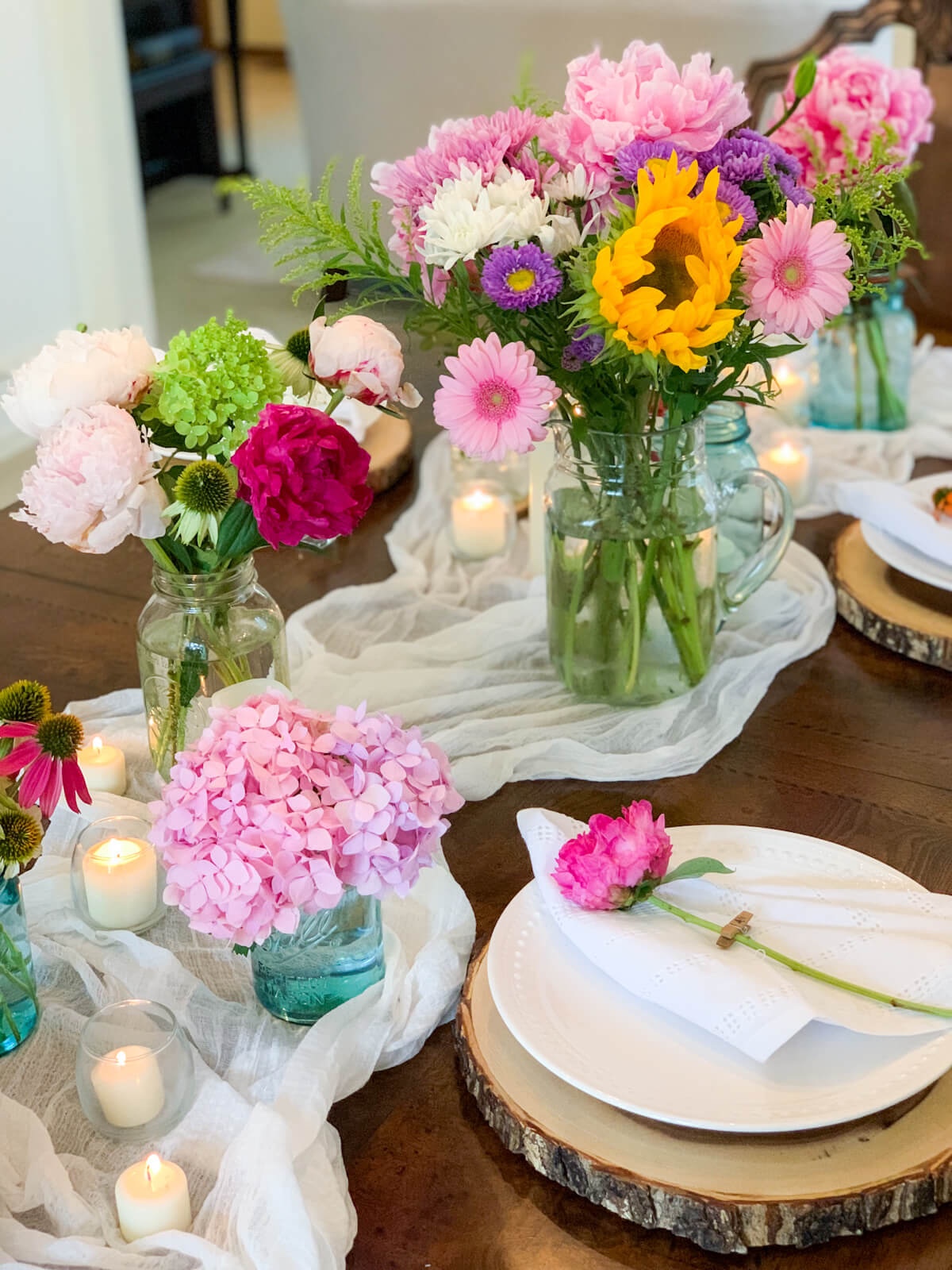 A place setting with a wood charger sits beside a summery country centerpiece.