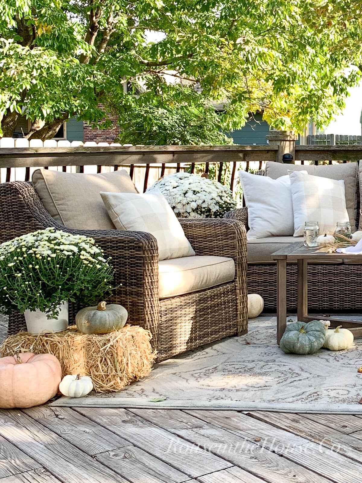 Outdoor fall decor on the back deck include cozy throw pillows, white mums, and heirloom pumpkins of various sizes.