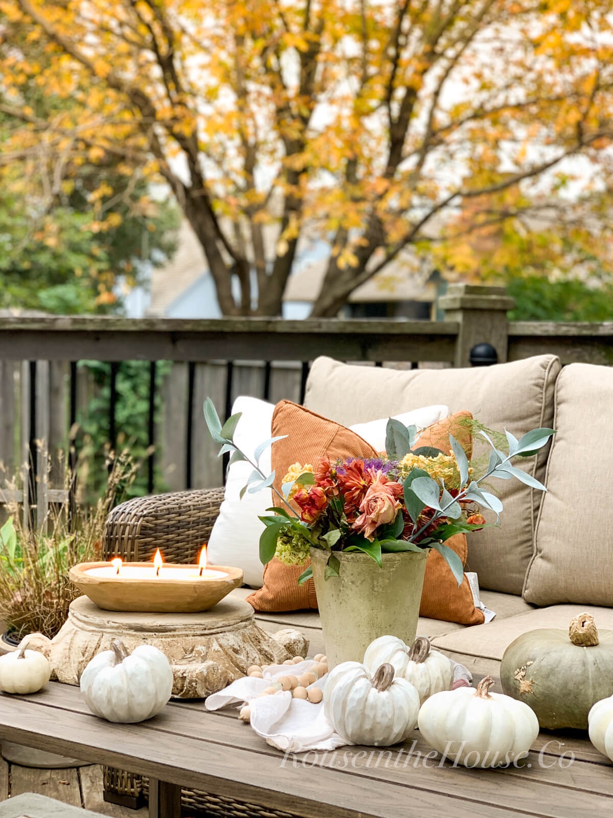 A dried fall flower arrangement is the outdoor decor on a patio coffee table.