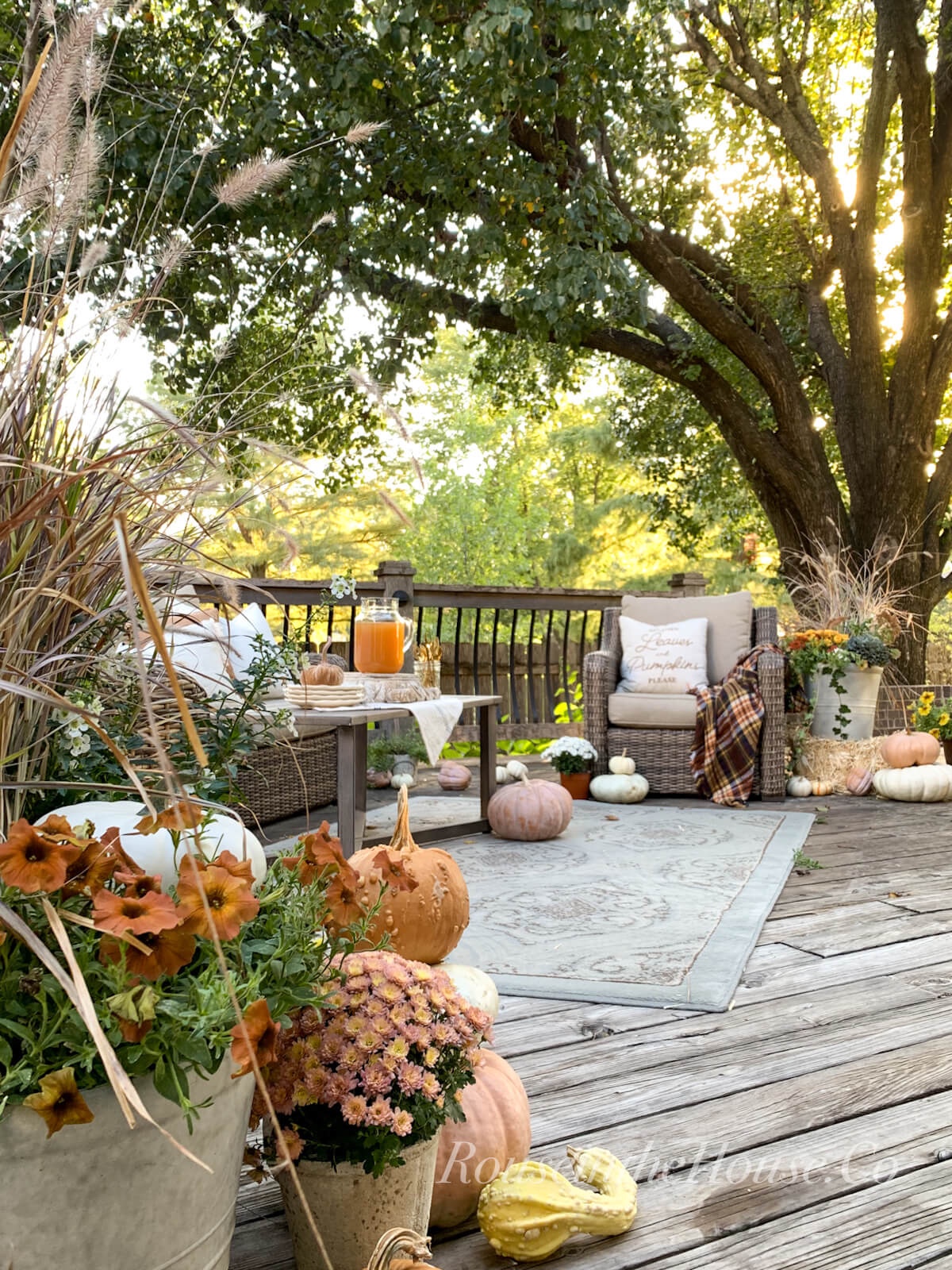 A outdoor wooden deck all decked out with nautral fall decor at sunset.  