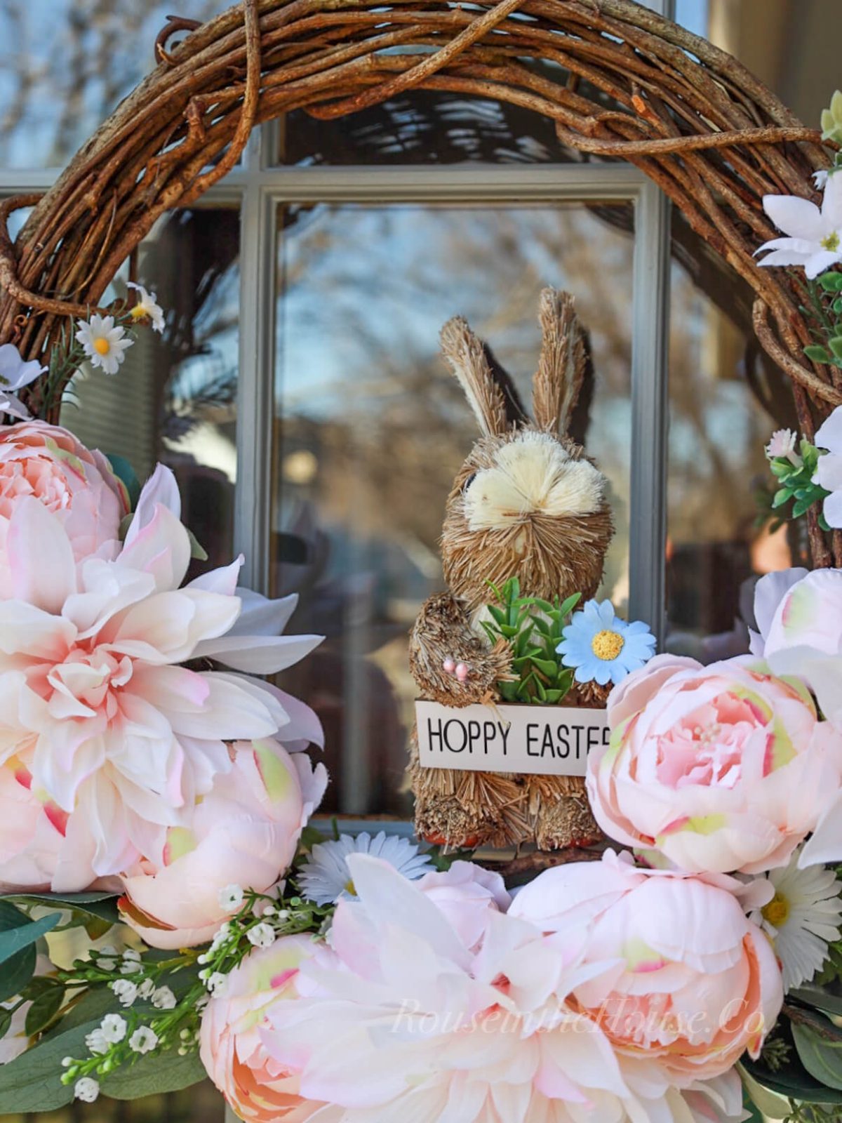 Pink Spring Flower Wreath with a Dollar Tree Sisal Bunny holding a sign that says "Hoppy Easter".