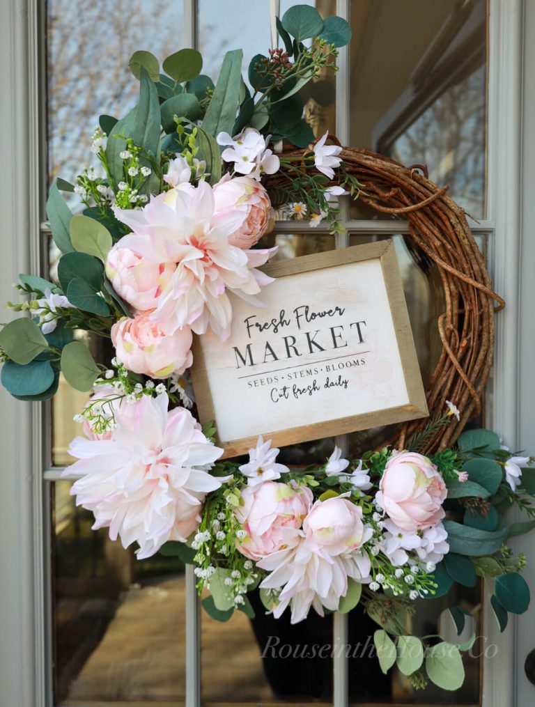 A diy faux flower wreath with a sign that reads "Fresh Flower Market" is hanging on a door.
