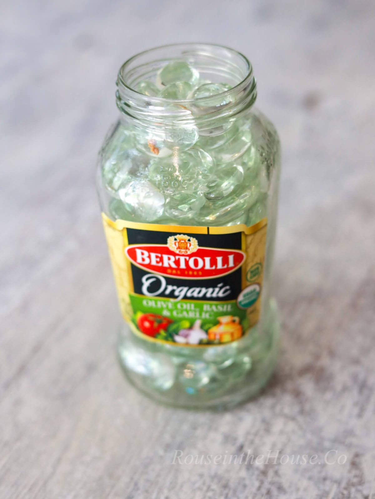 A Bertolli sauce jar that's been cleaned to repurpose for DIYing an etched glass flower vase.